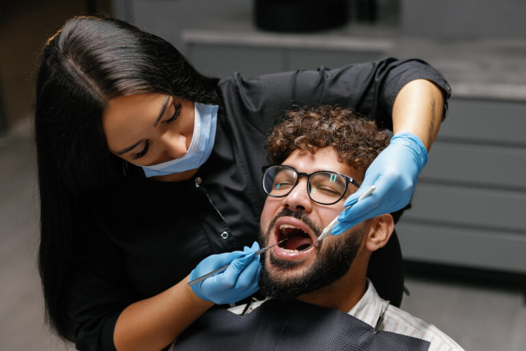 Dentist checking patient teeth during oral examination - dental headache and neck pain